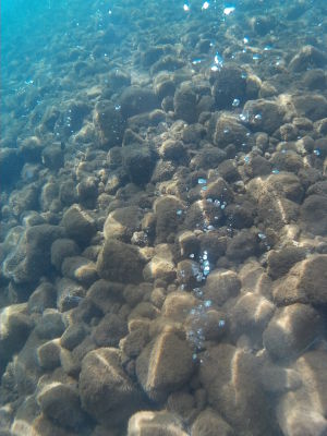 Bublinky unikajúceho plynu na morskom dne na Bubble Spa Beach