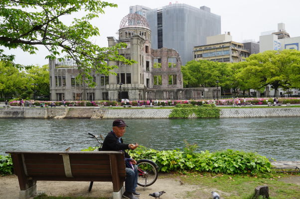 Dôchodca kŕmi vrabce pred Atómovým dómom v Hirošime